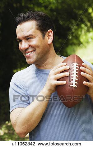 Stock Image - Close-up of a mature man holding a football. Fotosearch