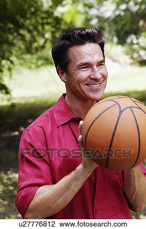 Stock Image - Close-up of a mature man holding a basketball. Fotosearch