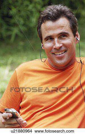 Close-up of a mature man listening to an MP3 player View Large Photo Image Picture - Close-up of a mature man listening to an MP3 player. Fotosearch