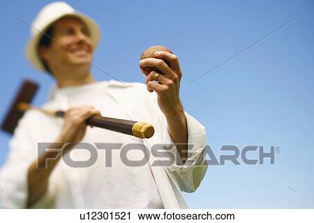 Low angle view of a mid adult man holding a croquet mallet and a ball View Large Photo Image Stock Image - Low angle view of a mid adult man holding a croquet mallet and a ball. Fotosearch