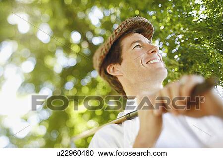 Low angle view of a mid adult man holding a golf club and smiling View Large Photo Image Stock Image - Low angle view of a mid adult man holding a golf club and smiling. Fotosearch