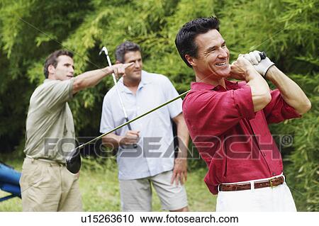 Mature man swinging a golf club with his friends standing behind him View Large Photo Image Stock Image - Mature man swinging a golf club with his friends standing behind him. Fotosearch