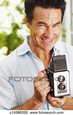 Portrait of a mature man holding a camera View Large Photo Image Stock Photograph - Portrait of a mature man holding a camera. Fotosearch