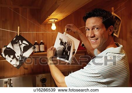 Portrait of a mature man holding photographs in a dark room View Large Photo Image Stock Photo - Portrait of a mature man holding photographs in a dark room. Fotosearch