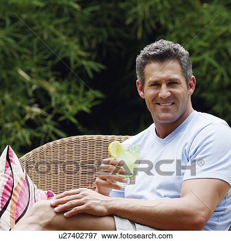 Portrait of a mid adult man holding a glass of lemonade and smiling View Large Photo Image Stock Photo - Portrait of a mid adult man holding a glass of lemonade and smiling. Fotosearch