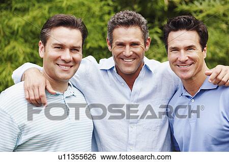 Stock Photograph - Portrait of a mid adult man with two mature men posing and smiling. Fotosearch