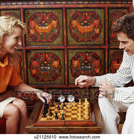 Stock Image - Side profile of a businessman and a businesswoman playing chess. Fotosearch