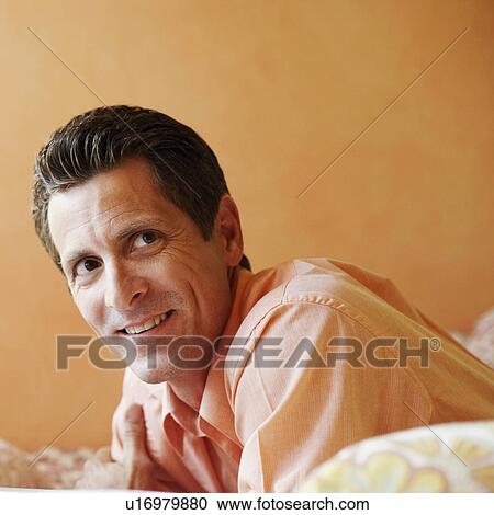 Close-up of a mature man lying on the bed and smiling View Large Photo Image Stock Image - Close-up of a mature man lying on the bed and smiling. Fotosearch