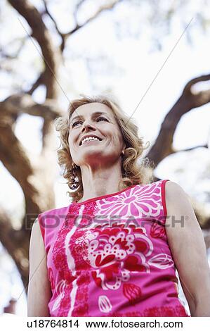 Picture - Low angle view of a mature woman smiling and looking away. Fotosearch