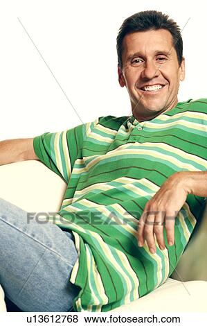 Stock Photo - Portrait of a mature man reclining on a couch and smiling. Fotosearch