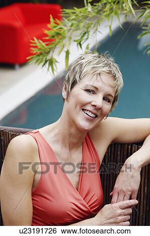 Portrait of a mature woman leaning against a fence and smiling View Large Photo Image Stock Photograph - Portrait of a mature woman leaning against a fence and smiling. Fotosearch
