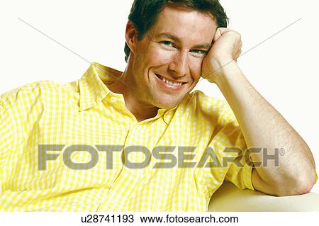 Stock Image - Portrait of a mid adult man smiling with his head in his hands. Fotosearch
