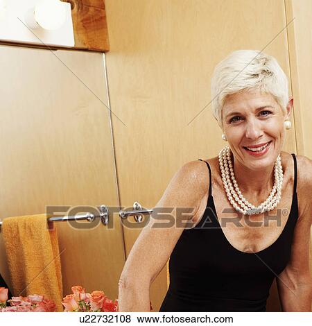 Stock Photo - Portrait of a senior woman sitting in front of a mirror and smiling. Fotosearch
