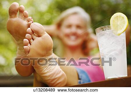 Close-up of a mature woman's foot with a glass of lemon juice beside her View Large Photo Image Stock Photo - Close-up of a mature woman's foot with a glass of lemon juice beside her. Fotosearch