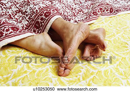 Close-up of the feet of a couple lying in bed View Large Photo Image Stock Image - Close-up of the feet of a couple lying in bed. Fotosearch
