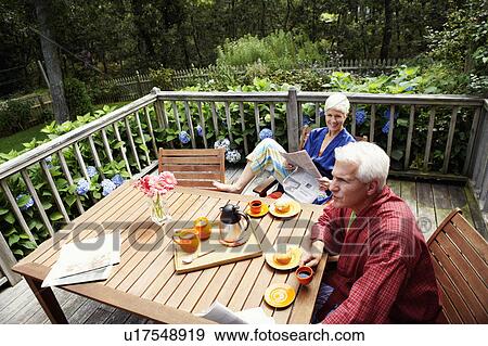 Stock Photo - High angle view of a mature man and a senior woman sitting at the table. Fotosearch