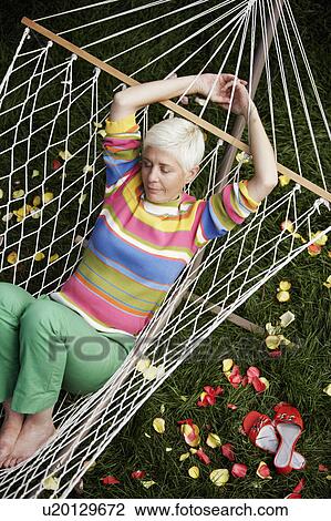 Stock Image - High angle view of a mature woman sleeping in a hammock. Fotosearch