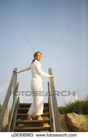 Stock Image - Low angle view of a mature woman standing on a staircase. Fotosearch