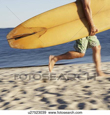 Low section view of a mature man holding a surfboard and walking on the beach View Large Photo Image Stock Photo - Low section view of a mature man holding a surfboard and walking on the beach. Fotosearch