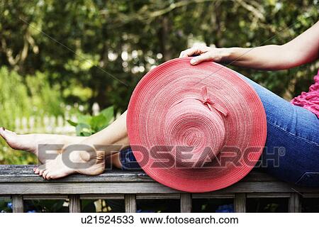 Low section view of a mature woman holding a hat and sitting on a railing View Large Photo Image Stock Image - Low section view of a mature woman holding a hat and sitting on a railing. Fotosearch