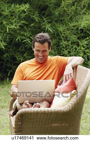 Stock Image - Mature man working on a laptop and smiling. Fotosearch