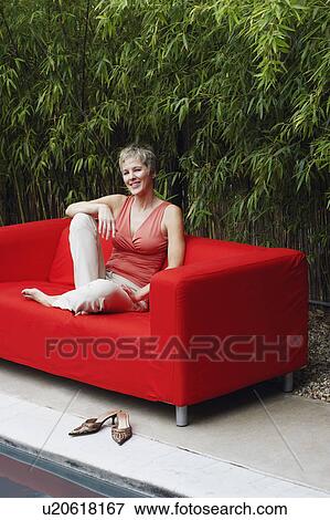 Stock Photo - Mature woman sitting in a couch and smiling. Fotosearch