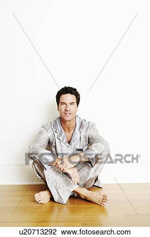 Stock Image - Portrait of a mature man sitting cross-legged on the floor. Fotosearch