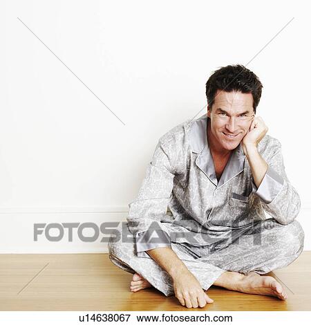 Stock Photo - Portrait of a mature man sitting cross-legged on the floor and smiling. Fotosearch