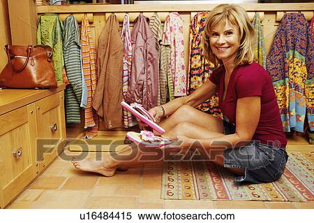 Stock Photography - Portrait of a mature woman holding a pair of flip-flops. Fotosearch