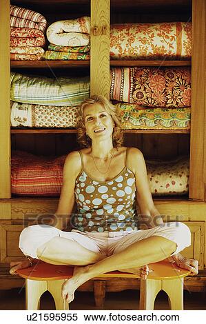 Stock Photography - Portrait of a mature woman sitting on the table and smiling. Fotosearch
