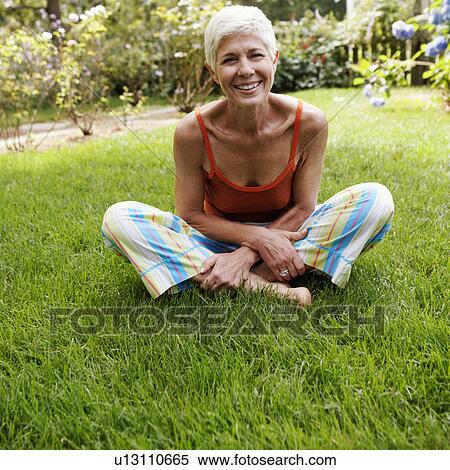 Stock Photography - Portrait of a senior woman sitting on grass. Fotosearch