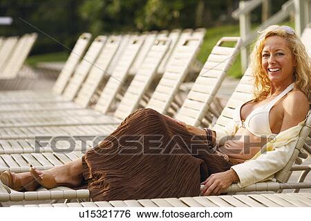 Stock Photograph - Side profile of a mature woman reclining on a lounge chair. Fotosearch