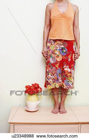 Stock Photo - Woman standing on a cabinet. Fotosearch