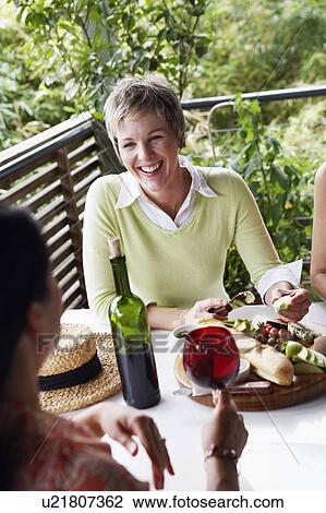 Stock Image - High angle view of two mature women sitting at the table and smiling. Fotosearch