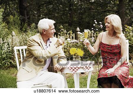 Mature couple looking at each other holding glasses of juice View Large Photo Image Picture - Mature couple looking at each other holding glasses of juice. Fotosearch