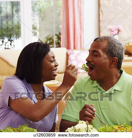 Stock Photo - Mature woman feeding salad to a mature man. Fotosearch