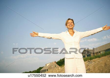 Stock Image - Mature woman smiling with her arms outstretched. Fotosearch