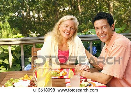 Portrait of a mature couple sitting at the table and smiling View Large Photo Image Stock Photo - Portrait of a mature couple sitting at the table and smiling. Fotosearch