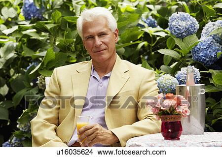 Picture - Portrait of a mature man holding a glass of juice. Fotosearch