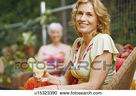 Portrait of a mature woman holding a glass of lemonade and smiling View Large Photo Image Stock Image - Portrait of a mature woman holding a glass of lemonade and smiling. Fotosearch
