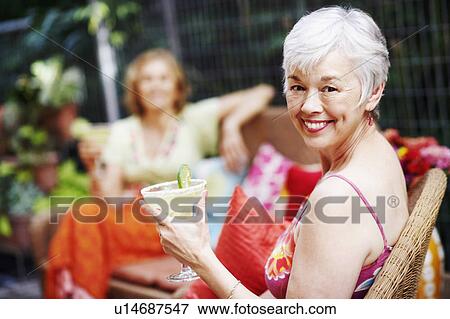 Stock Photo - Portrait of a mature woman holding a glass of lemonade and smiling. Fotosearch