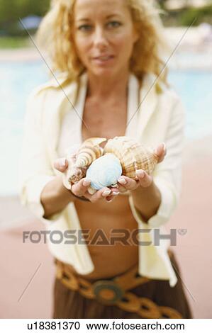 Portrait of a mature woman holding conch shells View Large Photo Image Stock Image - Portrait of a mature woman holding conch shells. Fotosearch
