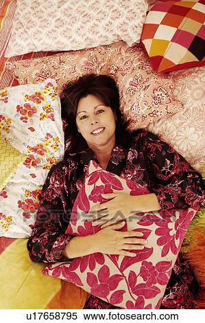 Portrait of a mature woman lying on the bed and smiling View Large Photo Image Stock Photography - Portrait of a mature woman lying on the bed and smiling. Fotosearch