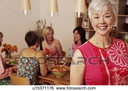 Portrait of a mature woman smiling and her friends sitting behind her View Large Photo Image Stock Photograph - Portrait of a mature woman smiling and her friends sitting behind her. Fotosearch