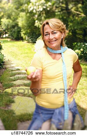 Portrait of a mature woman standing and holding a lemon View Large Photo Image Stock Photograph - Portrait of a mature woman standing and holding a lemon. Fotosearch