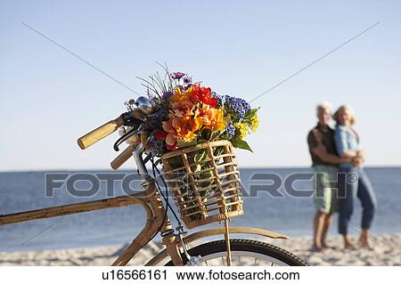 Close-up of a bicycle with a couple standing in the background View Large Photo Image Stock Image - Close-up of a bicycle with a couple standing in the background. Fotosearch