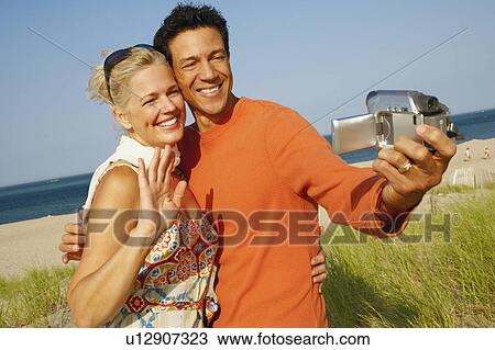 Close-up of a mature couple taking a picture of themselves on the beach View Large Photo Image Stock Image - Close-up of a mature couple taking a picture of themselves on the beach. Fotosearch