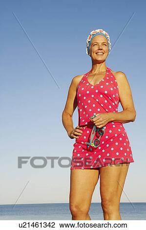 Low angle view of a mature woman standing on the beach and smiling View Large Photo Image Stock Image - Low angle view of a mature woman standing on the beach and smiling. Fotosearch