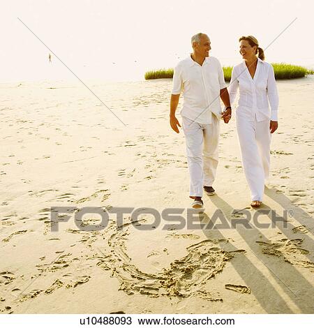 Mature couple holding hands and walking on the beach View Large Photo Image Stock Image - Mature couple holding hands and walking on the beach. Fotosearch