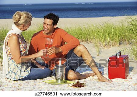 Mature couple sitting on the beach and holding champagne flutes View Large Photo Image Stock Image - Mature couple sitting on the beach and holding champagne flutes. Fotosearch